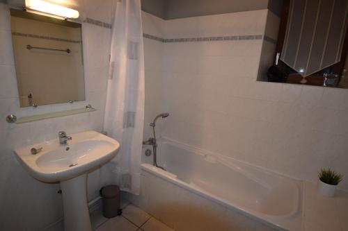 a white bathroom with a sink and a bath tub at VAUJANYLOCATIONS - Chalet Louise in Vaujany