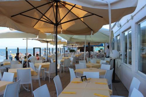 un restaurante con mesas blancas, sillas y sombrillas blancas en Happy Camp Mobile Homes in Camping Village Rosapineta en Rosolina Mare