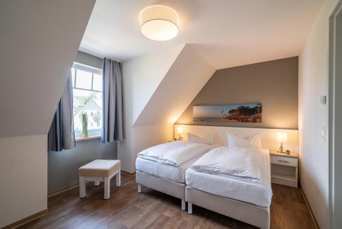 ein Schlafzimmer mit einem großen weißen Bett und einem Fenster in der Unterkunft StrandResort Markgrafenheide in Warnemünde