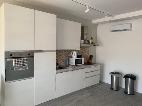 a kitchen with white cabinets and a microwave at St Julians Apartment 2 in St Julian's