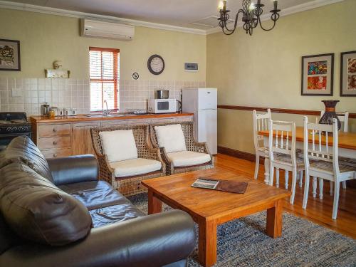 a living room with a couch and a table at Berluda Farmhouse and Cottages in Oudtshoorn