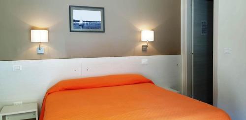 a bedroom with an orange bed with two lights on the wall at Dépendance Lisa in Pineto
