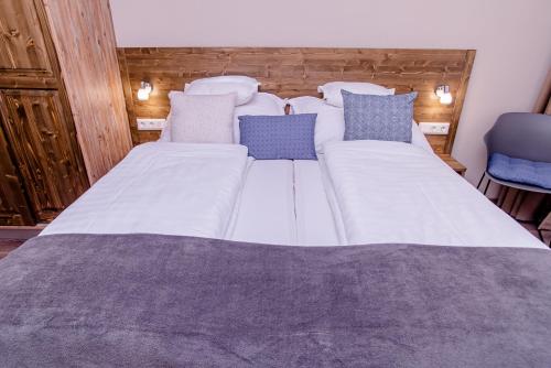 a large white bed with blue pillows on it at Három a Kislány Panzió in Hévíz