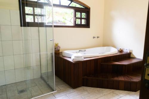 a bathroom with a tub and a glass shower at Hotel Naturalis in Paranaguá