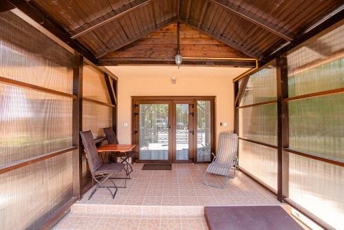 a screened in porch with chairs and a table at Három a Kislány Panzió in Hévíz