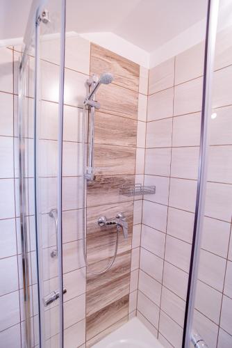 a shower in a bathroom with pink tiles at Három a Kislány Panzió in Hévíz