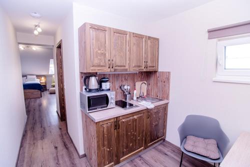 a kitchen with wooden cabinets and a microwave at Három a Kislány Panzió in Hévíz