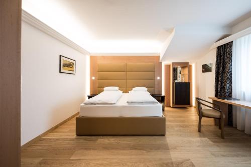 um quarto de hotel com duas camas e uma secretária em Hotel Haus am Hang em Caldaro