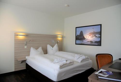 a hotel room with a white bed with a picture on the wall at Appartement Vermietung Brunner in Rostock