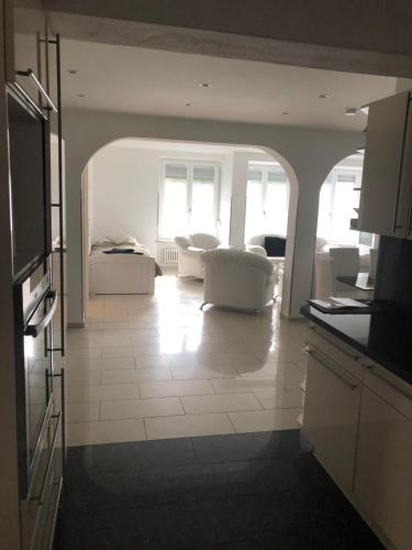 a living room with two white chairs and a kitchen at Ferienwohnung Amperblick Fürstenfeldbruck in Fürstenfeldbruck