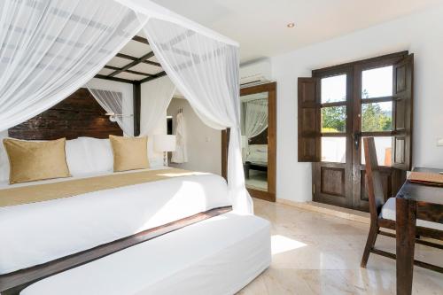 a bedroom with a white bed and a desk at Agroturismo Atzaró in Santa Eularia des Riu
