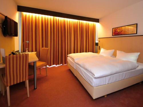a hotel room with a large bed and a desk at Seligweiler Hotel & Restaurant in Ulm