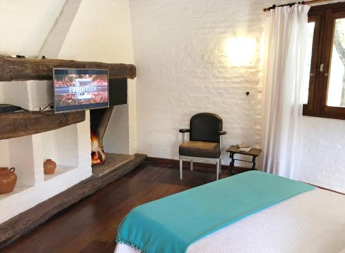 a bedroom with a bed and a tv and a chair at Posada del Huerto in La Carrodilla