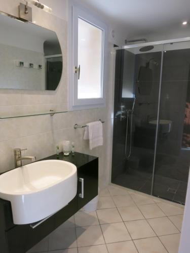 La salle de bains est pourvue d'un lavabo blanc et d'une douche. dans l'établissement Prea Gianca, à Bonifacio