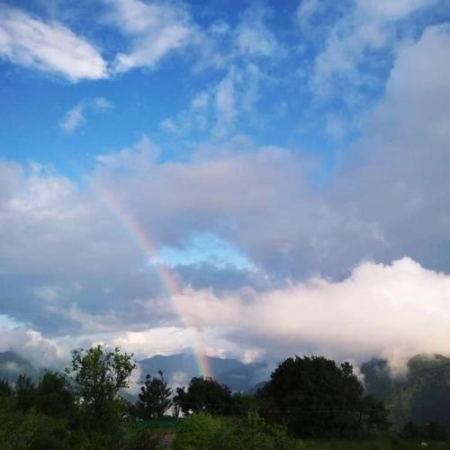 a rainbow in the sky with clouds and trees at Karinya Villas in Nainital