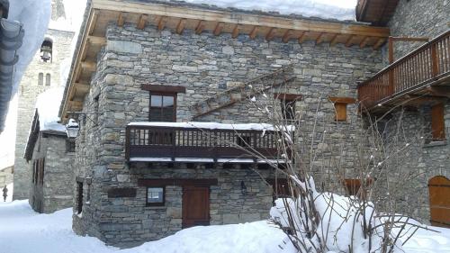 a stone building with a balcony in the snow at La Centaurée in Bonneval-sur-Arc