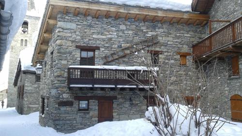 um edifício de pedra com uma varanda na neve em La Centaurée em Bonneval-sur-Arc