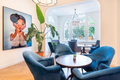 a waiting room with blue chairs and tables and a painting at Strandhotel Ahlbeck in Ahlbeck