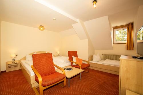 a bedroom with a bed and two chairs and a table at Hotel Post Leutkirch in Leutkirch im Allgäu