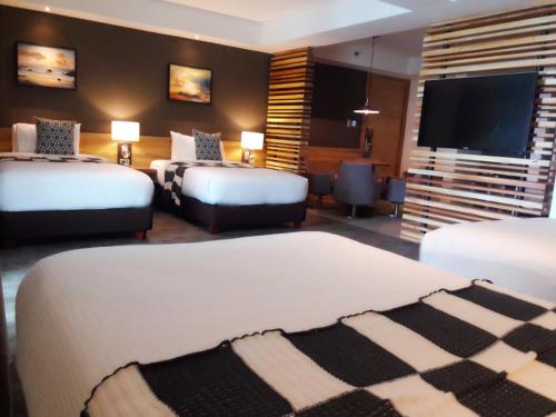 a hotel room with two beds and a flat screen tv at Escala Tagaytay in Tagaytay