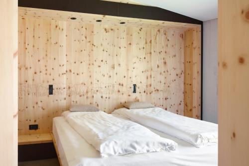 two beds in a room with a wooden wall at Alpine Lodge Chesa Plattner in Pontresina