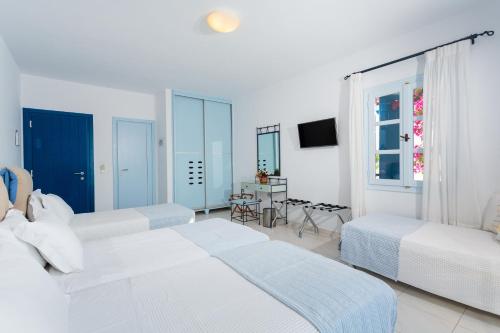 a white bedroom with two beds and a table at Pyrgaki Hotel in Parikia