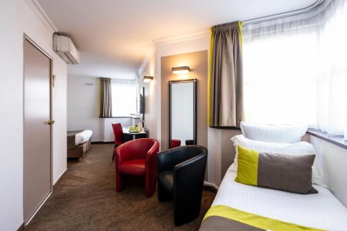 a hotel room with a bed and chairs and a mirror at Campanile Reims Centre - Cathedrale in Reims