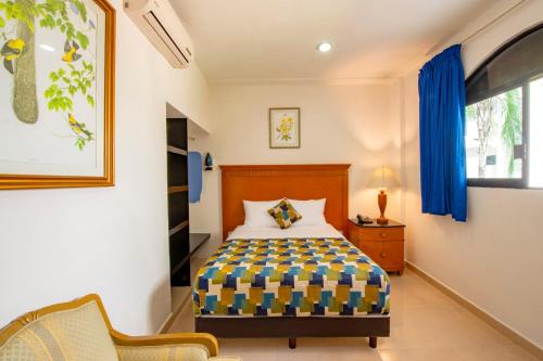 a bedroom with a bed and a chair and a window at Hotel Embajadores in Mérida