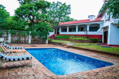 een zwembad met 2 ligstoelen en een huis bij The White House of Victoria Falls in Victoria Falls