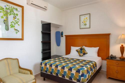 a bedroom with a bed and a chair at Hotel Embajadores in Mérida