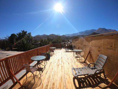 a wooden deck with tables and chairs and the sun at Hostal Michel in Vicuña