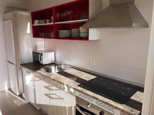 a kitchen with red cabinets and a sink at Los Acebos in Otero de Herreros