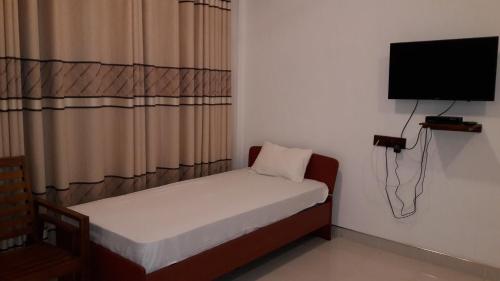 a small room with a small bed and a flat screen tv at Risenlak Holiday Resort in Polonnaruwa