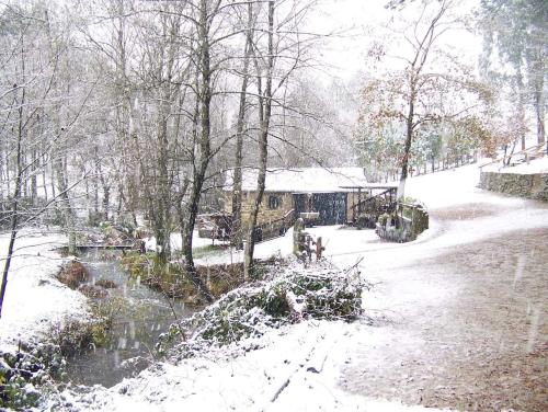 una casa está cubierta de nieve junto a un río en Molino de Louzao, en Palas de Rei 