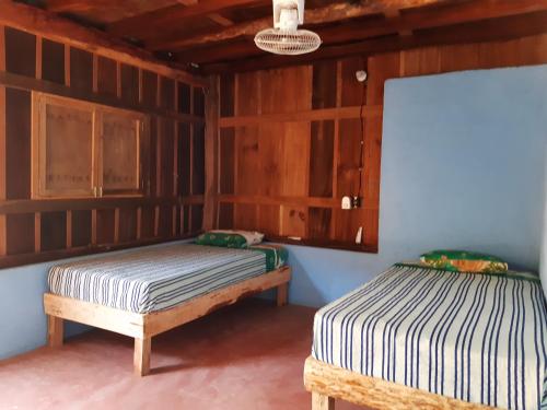 two beds in a room with wooden walls at Cabañas jaysur in Barra de la Cruz