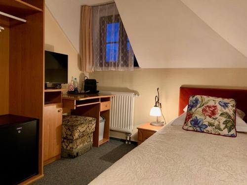 a bedroom with a bed and a desk and a television at Hotel Wenus in Kazimierz Dolny