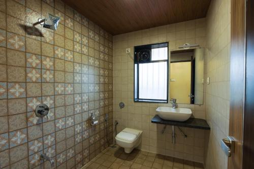 bagno con servizi igienici, lavandino e specchio di City Palace Resort a Lonavala