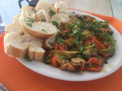 a plate of food with vegetables and bread on an orange tray at Pousada Ilha Sul in Cananéia