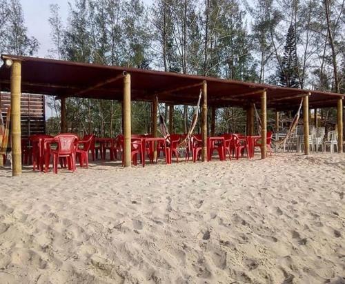 a group of red tables and chairs on the beach at Pousada Ilha Sul in Cananéia