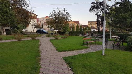 a park with benches and grass and a pole at Apartament Ema Baile Felix in Baile Felix