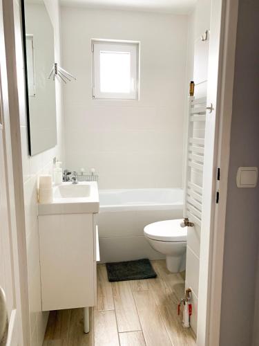 a white bathroom with a sink and a toilet at Apartament Kotwica in Gdynia