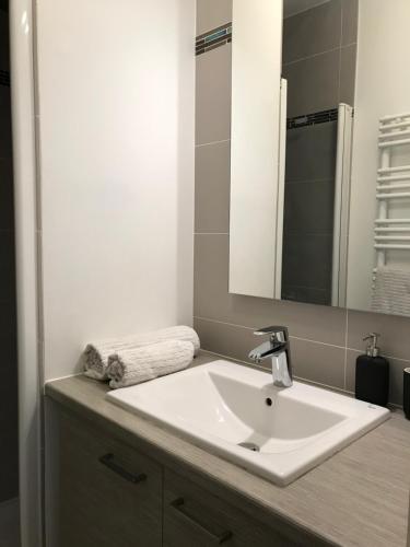 y baño con lavabo blanco y espejo. en Chambre d'hôte Naos Homestay, en Boulogne-Billancourt