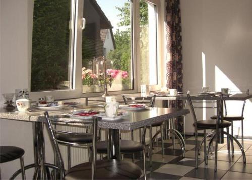 d'une salle à manger avec une table, des chaises et une fenêtre. dans l'établissement Hotel Garni Haus Schönberger, à Heiligenhaus