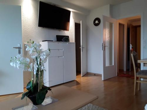 a living room with a white cabinet and a vase with flowers at Apartmenthotel Hohegeiß Kasing MIT FREIEM WLAN und Schwimmbad in Hohegeiß