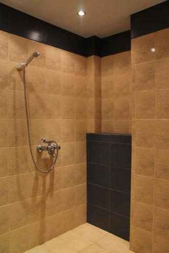 a bathroom with a shower with a hose on the wall at Edelvais Guest House in Primorsko