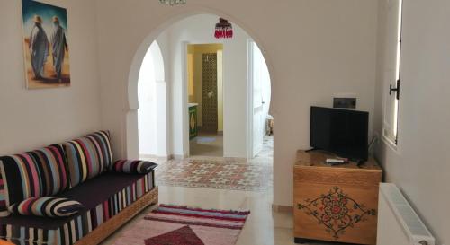 a living room with a couch and a tv at Dar El Jerbi in Mezraya