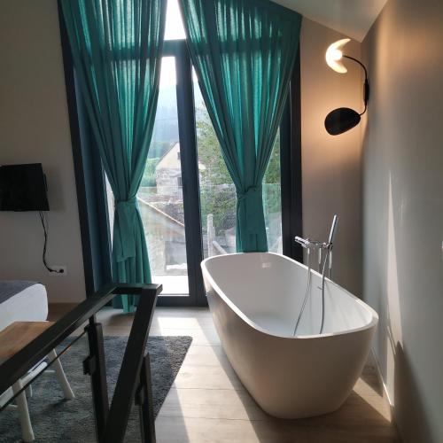 a bathroom with a tub in front of a window at Eidos da laxe in Sela