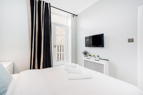 Un dormitorio blanco con una cama blanca y una ventana en Lovely 2 bedroom apartment in Notting Hill, en Londres