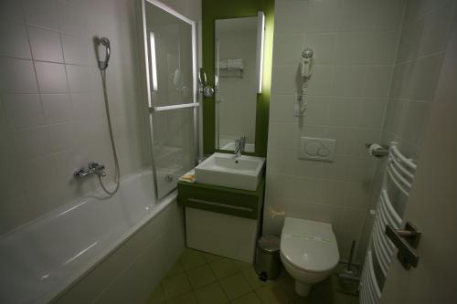 La salle de bains est pourvue d'un lavabo, de toilettes et d'une douche. dans l'établissement Hotel EMPIRE, à Trnava