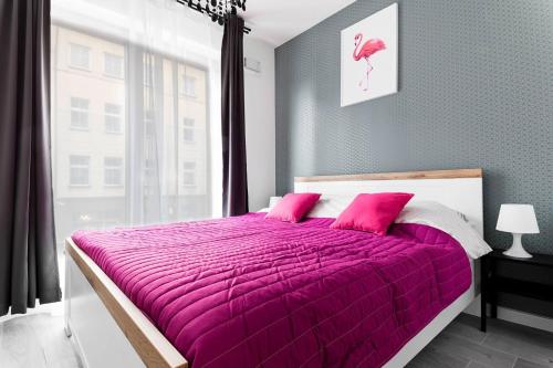 a purple bed with pink pillows in a bedroom at Room Tour Rakowicka 14a- Free Garage in Krakow